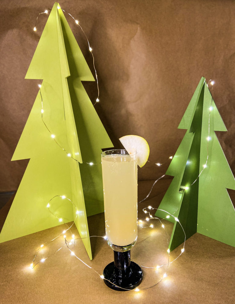pear and ginger fizz cocktail in a tall glass in front of a festive background